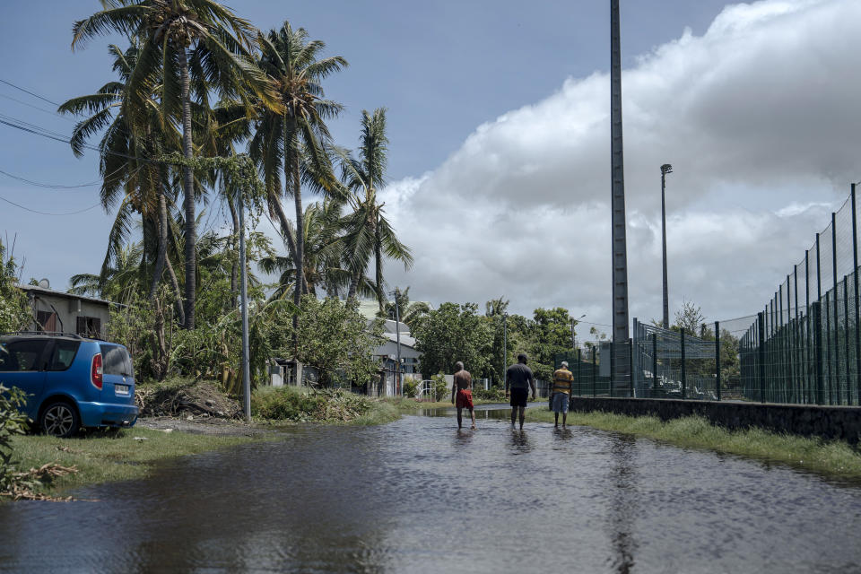 Men walk on a submerged street in the town of Saint-Paul, on the French Indian Ocean island of Reunion, Tuesday, Jan. 16, 2024. Tropical cyclone Belal had battered the French island of Reunion, where the intense rains and powerful winds left about a quarter of households without electricity after hitting Monday morning, according to the prefecture of Reunion. (AP Photo/Lewis Joly)