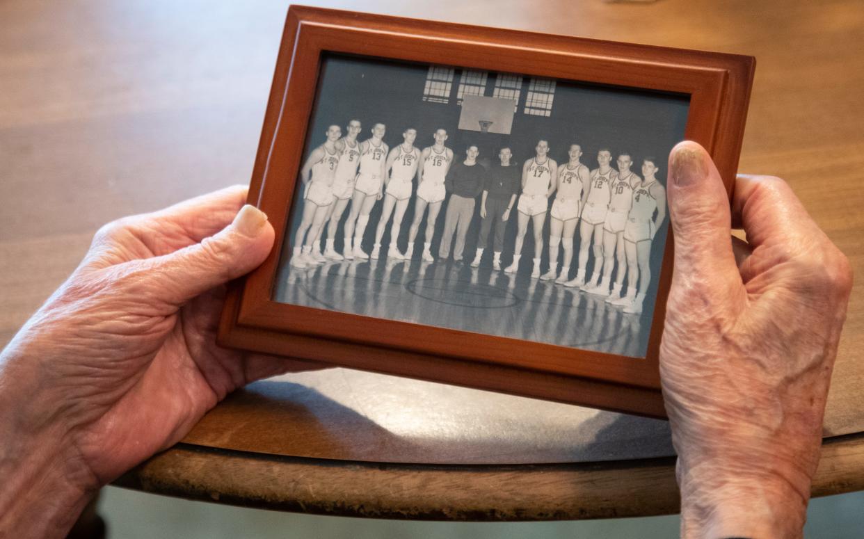 Bill Elbert holds a photo from the college basketball team he played on at St. Joseph's, Tuesday, March 26, 2024, at his home in West Lafayette, Ind.