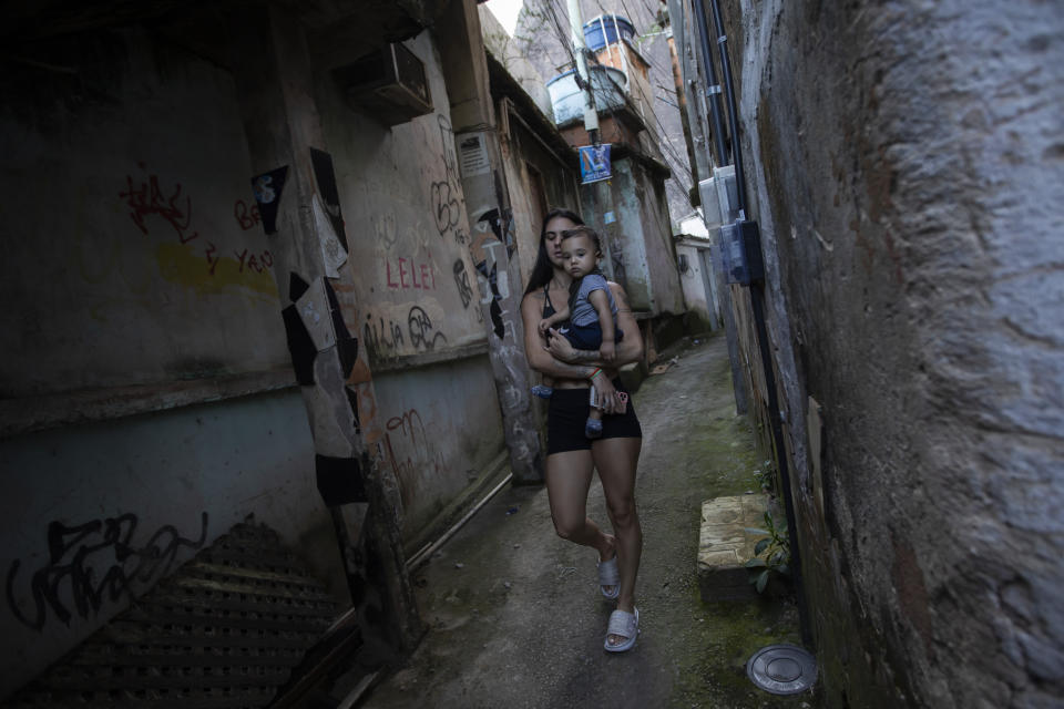 La clavadista brasileña Giovanna Pedroso camina con su hijo Nicolás Pedros en la favela Chacara do Ceu de Río de Janeiro, el miércoles 11 de octubre de 2023. Pedroso competirá en los Juegos Panamericanos de Chile. (AP Foto/Bruna Prado)