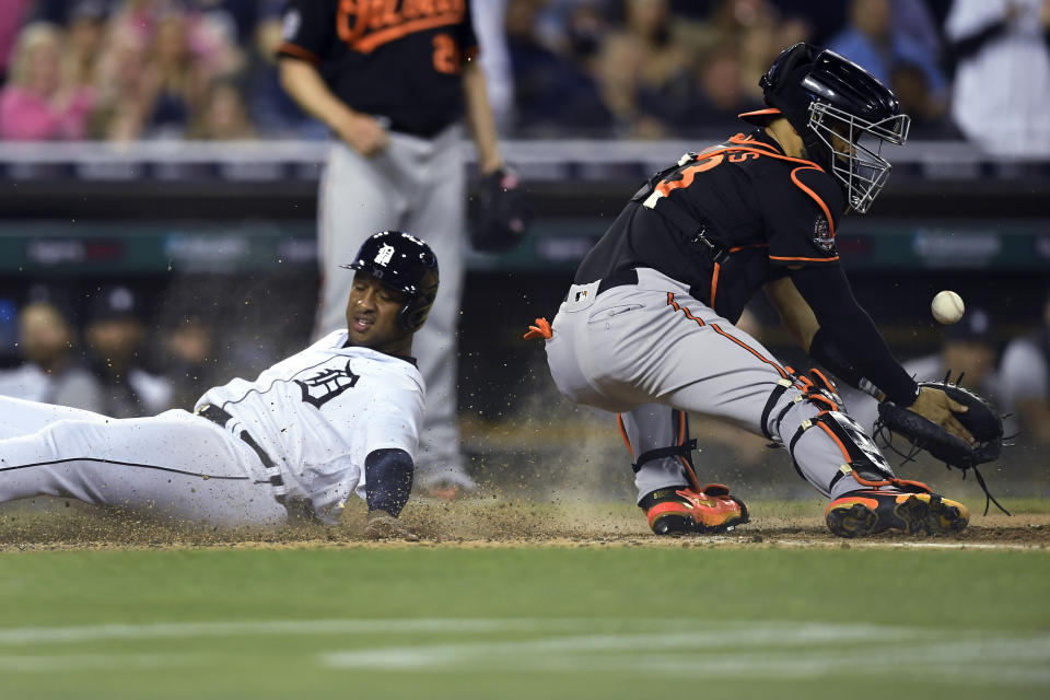 Detroit Tigers' Jonathan Schoop, left, scores on a double by Willi Castro as Baltimore Orioles catcher Robinson Chirinos loses control of the ball during the sixth inning of a baseball game Friday, May 13, 2022, in Detroit. (AP Photo/Jose Juarez)