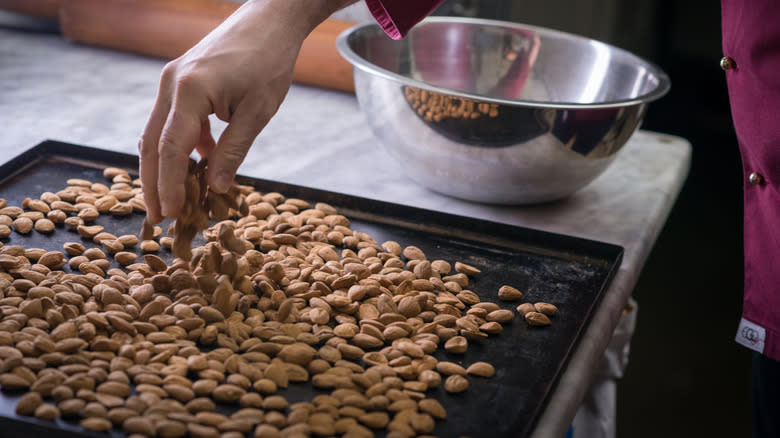 A hand places almond on a baking tray