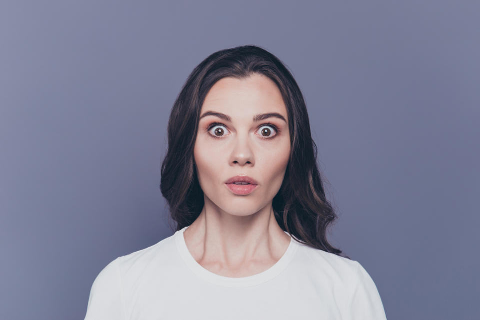 Boo! Portrait of attractive pretty charming stylish afraid brunette curly-haired girl in white t-shirt with staring big eyes, isolated over grey background