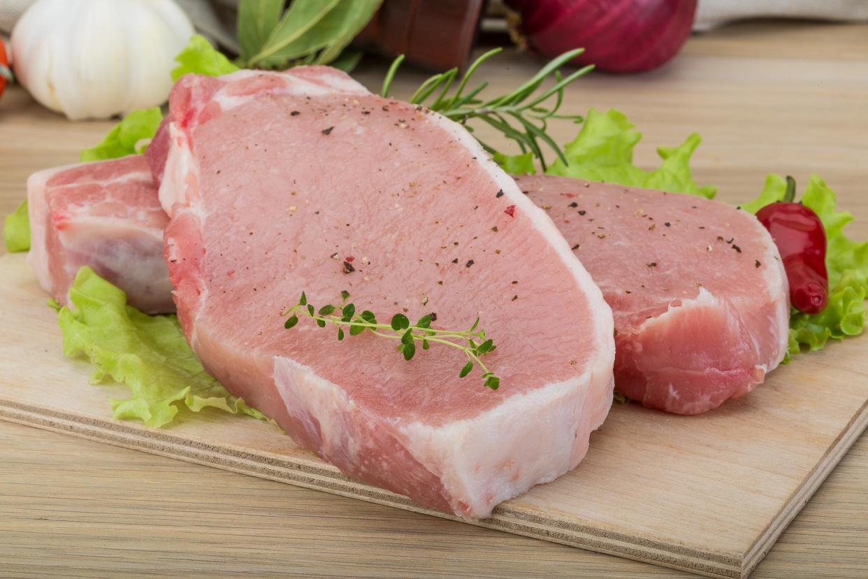 raw pork steak with herbs on table