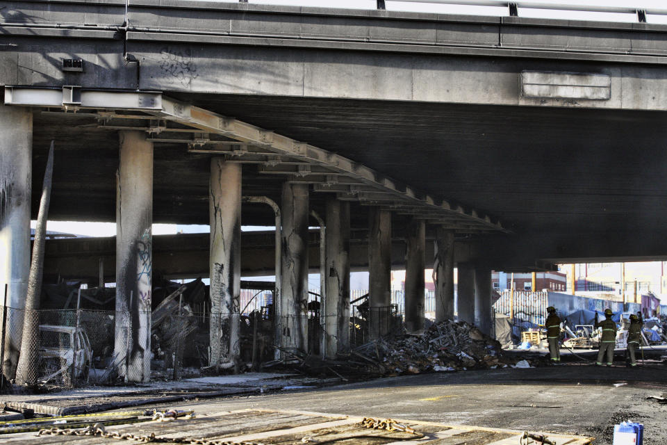 Los Angeles firefighters mop up from a fire under Interstate 10 that severely damaged the freeway in an industrial zone near downtown Los Angeles, Saturday, Nov. 11, 2023. Authorities say firefighters have mostly extinguished a large blaze that burned trailers, cars and other things in storage lots beneath a major highway near downtown Los Angeles, forcing the temporary closure of the roadway. (AP Photo/Richard Vogel)