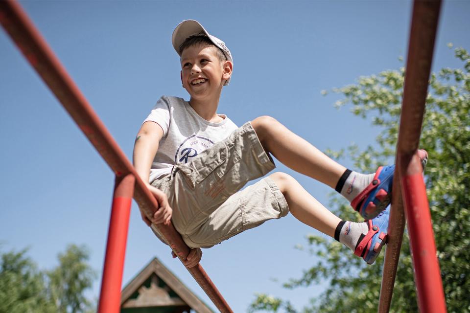 A boy smiles as he plays on the playground on June 20, 2022 near Kyiv, Ukraine. The goal of the 7fields camp, which is near Zalissia National Nature Park, is to support the children of families displaced from other parts of Ukraine since the February 24 invasion, but who are remaining in the country. Over the summer, the camp aims to support 300 children between the ages of 7 and 15, with activities like swimming pools, tennis, soccer, yoga, chess and craft-making, in addition to therapy sessions.