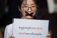 Nalinrat Tuthubthim, 20, a student, who claims she was sexually abused by a teacher, has her mouth covered with tape during a rally in Bangkok