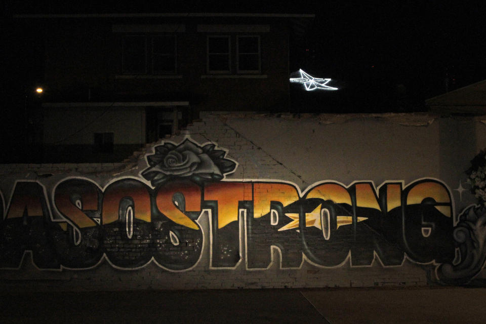 In this May 7, 2020, photo, an "El Paso Strong" mural is seen at night in El Paso, Texas. Gabe Vasquez and Justin Martinez painted the mural in August after the mass shooting at a Walmart on that killed 23 people. The star painted in the mural's letters can be seen in the background on the southern slope of the Franklin Mountains. (AP Photo/Cedar Attanasio)