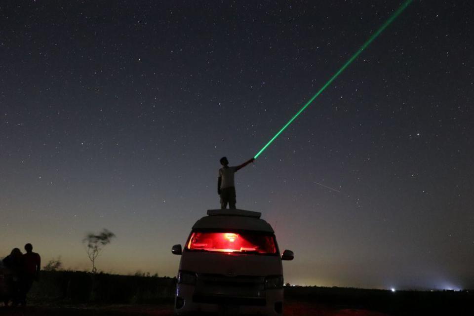 A person is playing with a laser while watching the galaxy and stars in Faiyum, Egypt, on 13 August.