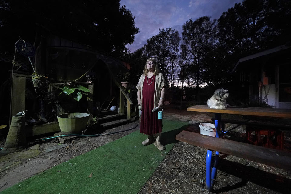 Joan Martin poses for a portrait with her Bichon Frise named Brigeet in the backyard of her home in Picayune, Miss., Wednesday, Nov. 11, 2020. When she heard that Joe Biden was declared the winner of the presidential election, the retired nurse and avowed supporter of President Donald Trump was deeply unsettled. To steel herself, she thought about how her household weathered Hurricane Katrina, when it battered her hometown of Picayune, in 2005. (AP Photo/Gerald Herbert)