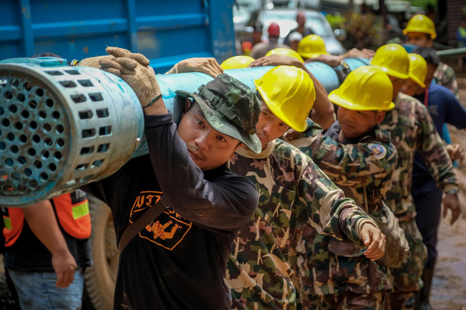 <p>Rescue workers carry heavy water-pumping equipment into Tham Luang Nang Non cave on July 1, 2018, in Chiang Rai, Thailand, as they looked for alternative ways into a flooded cave in the search for 12 boys and their soccer coach. (Photo: Linh Pham/Getty Images) </p>