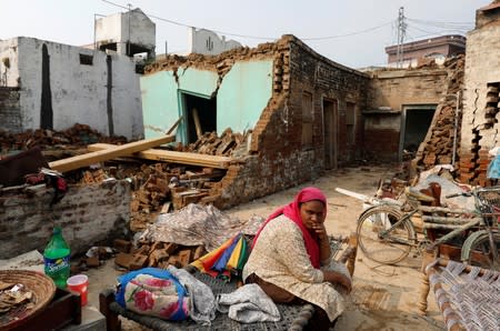 A woman sits with his belongings in an open space at her damaged house after an earthquake in Jatlan, Mirpur