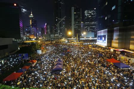 Pro-democracy protesters sing and wave their mobile phones as they block a main road during a rally outside government headquarters in Hong Kong in this October 10, 2014 file photo. REUTERS/Bobby Yip/Files