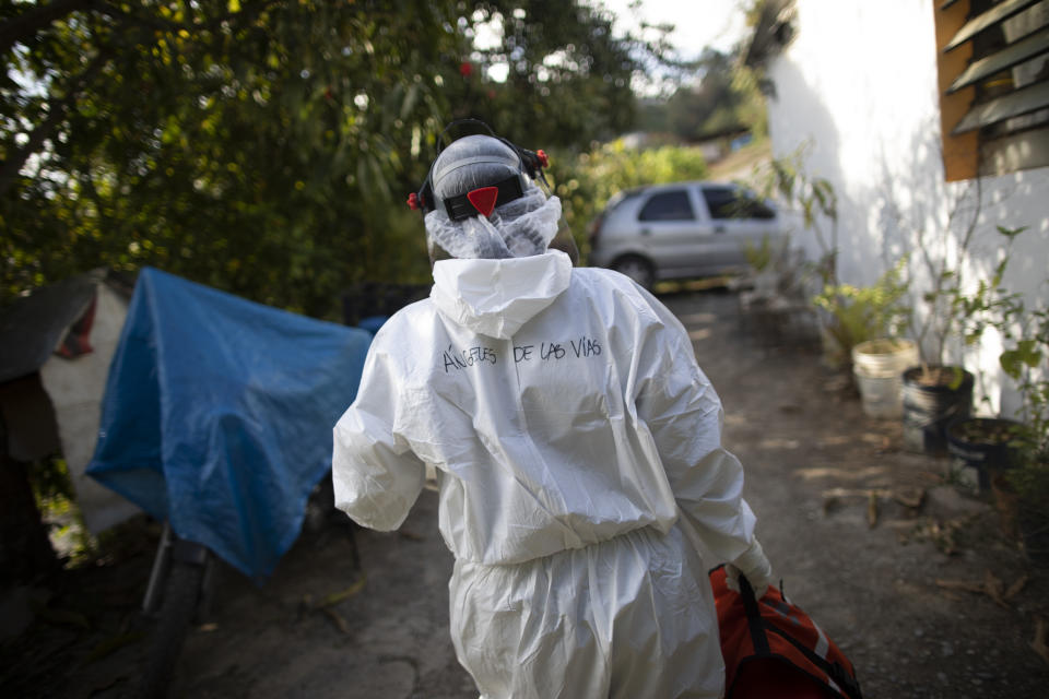 Wearing a biosecurity suit, Dr. Debora Mejia, an Angels of the Road volunteer, walks out of a house after visiting two COVID-19 patients in Caracas, Venezuela, Wednesday, Feb. 3, 2021. Each day brings on average three to four calls, and the new coronavirus pandemic means that at least one of those is a request to take a patient with trouble breathing to a hospital. (AP Photo/Ariana Cubillos)