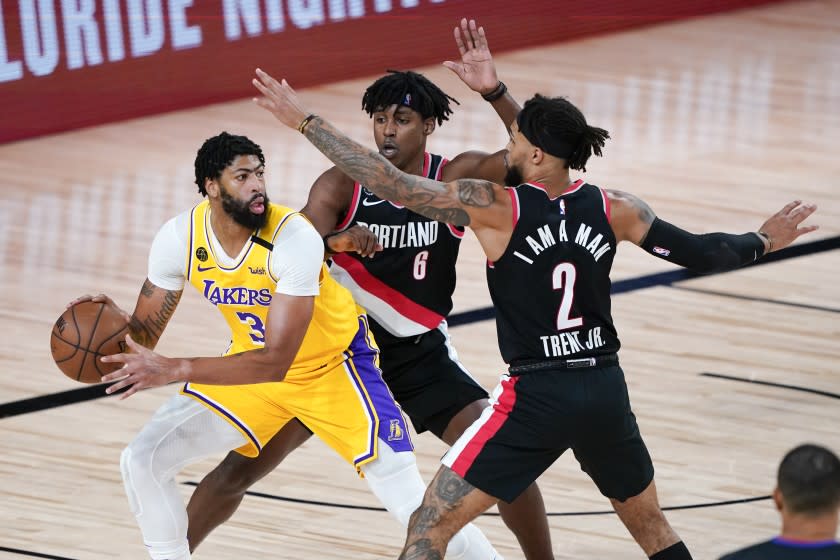 Los Angeles Lakers' Anthony Davis (3) looks for a way past Portland Trail Blazers' Jaylen Hoard (6) and Gary Trent Jr. (2) during the first half of an NBA basketball first round playoff game Saturday, Aug. 29, 2020, in Lake Buena Vista, Fla. (AP Photo/Ashley Landis)