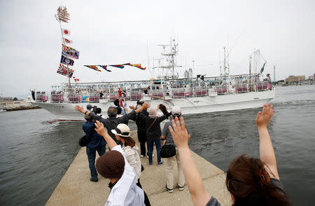 Relatives of a squid fishing crew wave, as the ship departs a port in Sakata, Japan, June 6, 2018. REUTERS/Issei Kato/Files
