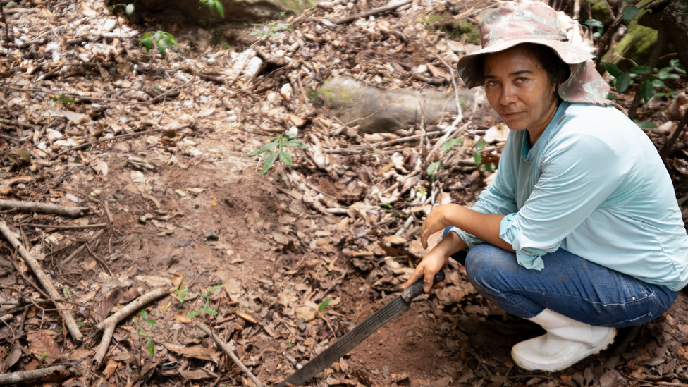 Catarina Oliveira de Silva points down at what used to be a lake