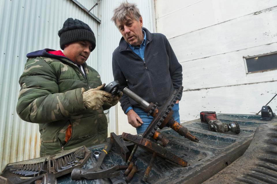 Roberto Tecpile, left, a Mexican immigrant, replaces the bearings while repairing an irrigator with the help of dairy farm owner John Rosenow at Rosenholm Dairy in Cochrane.