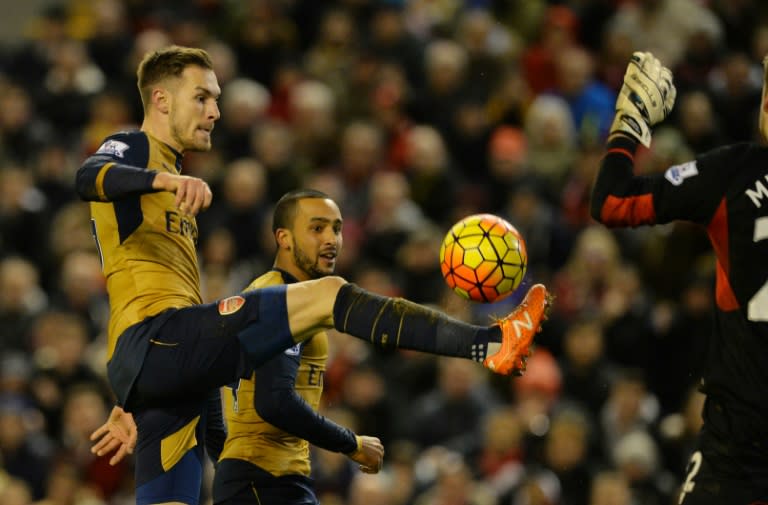 Arsenal's Aaron Ramsey (L) chips the ball over the top of Liverpool's goalkeeper Simon Mignolet during their English Premier League match, at Anfield stadium in Liverpool, on January 13, 2016