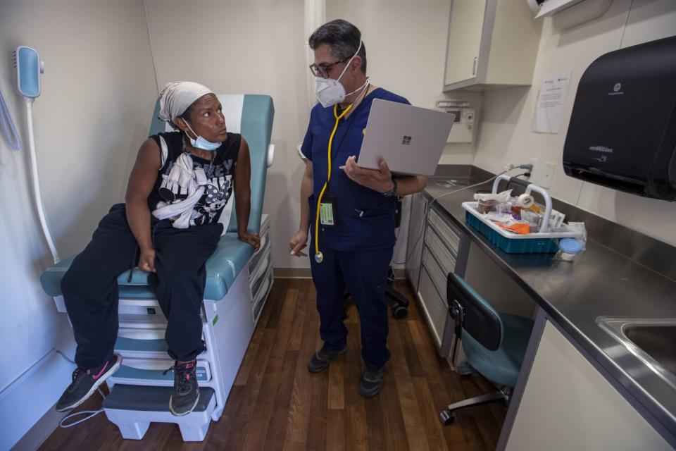 A doctor in scrubs speaks with a patient