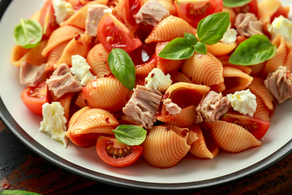 Conchiglie Tuna pasta with tomato sauce, feta cheese and basil on wooden table. healthy food.