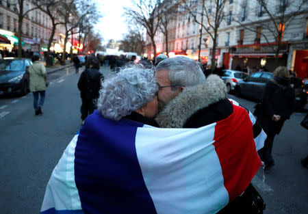 People wrapped in a French flag hug as they attend a gathering, organised by the CRIF Jewish organisation, in memory of Mireille Knoll, in Paris, France, March 28, 2018. REUTERS/Gonzalo Fuentes