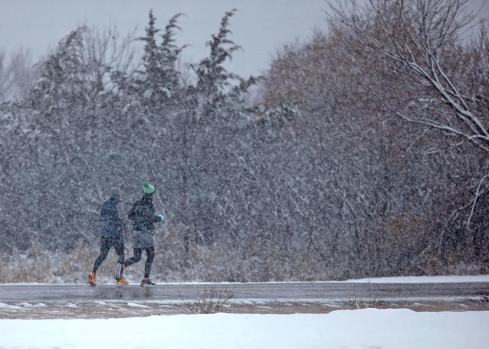 People run Tuesday at Mitch Park in Edmond. A winter storm brought snow to the metro area.