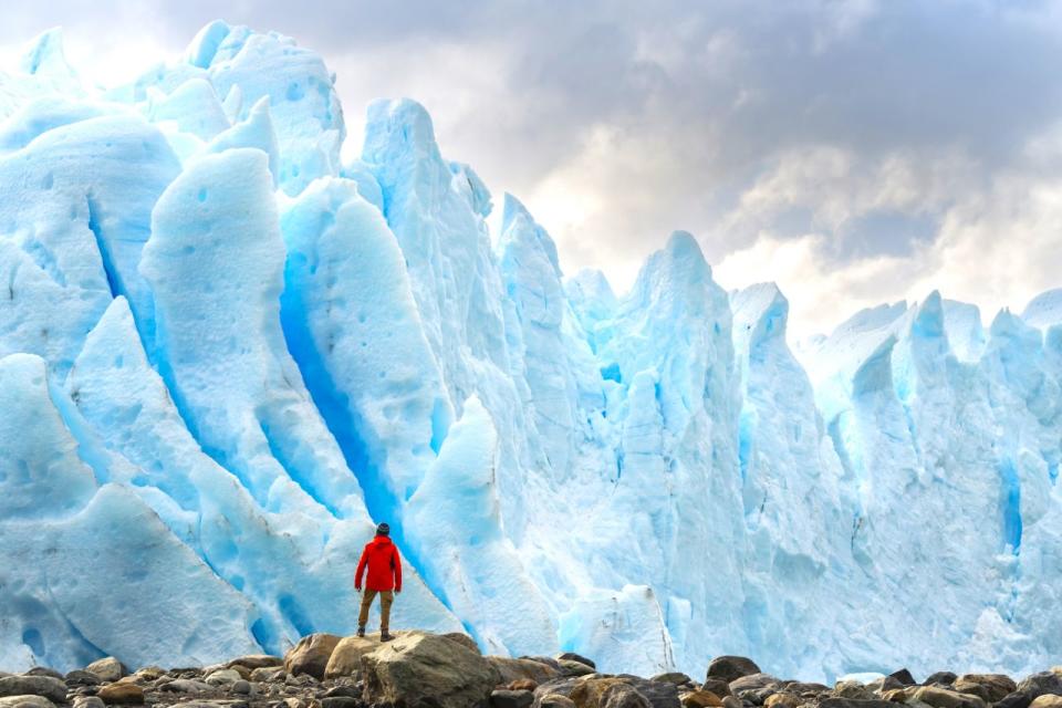 Primer plano de un hombre parado delante de las formaciones de hielo azul de Perito Moreno, en la provincia de Santa Cruz, Argentina. (Getty)