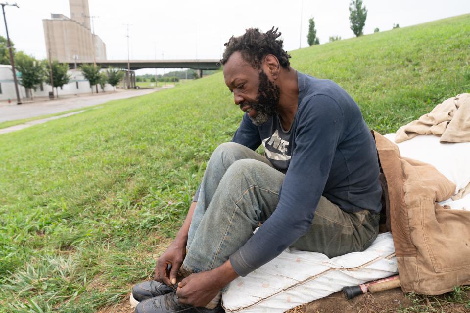 Eddie Perkins tightens his shoes Friday while sitting on a mattress on which he's been sleeping southwest of the Topeka Rescue Mission homeless shelter operated by TRM Ministries.