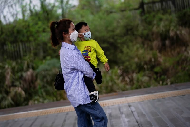Chen Ting, 28, and her 3 years old son wear face masks at a railway station in Xianning of Hubei province