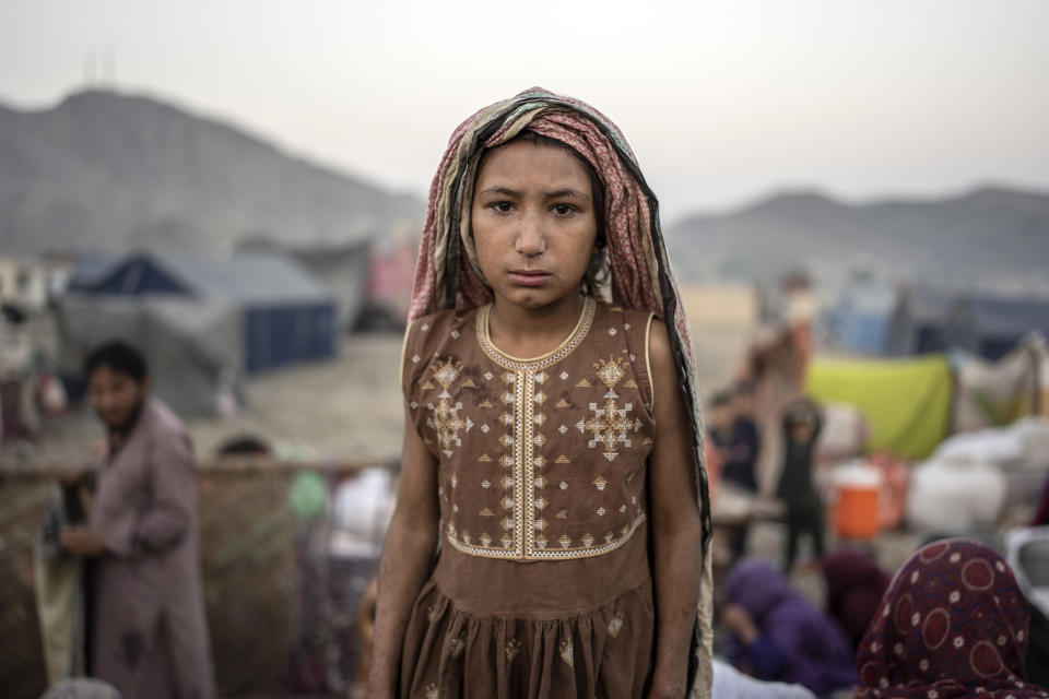 An Afghan refugee girl stands for a photo in a camp near the Torkham Pakistan-Afghanistan border in Torkham, Afghanistan, Saturday, Nov. 4, 2023. A huge number of Afghans refugees entered the Torkham border to return home hours before the expiration of a Pakistani government deadline for those who are in the country illegally to leave or face deportation. (AP Photo/Ebrahim Noroozi)