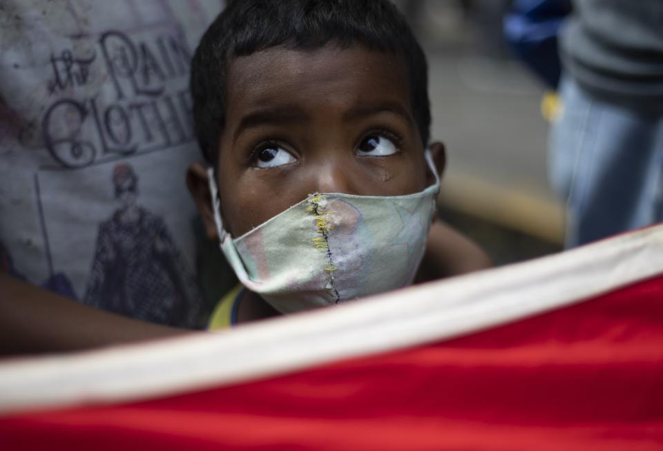 A youth attends a teachers' demonstration for higher pay in Caracas, Venezuela, Wednesday, Oct. 21, 2020. Some health workers also joined the protest and complained about their salaries of about $4 dollars a month, amid the COVID-19 pandemic. Teachers earn about $2 dollars a month. (AP Photo/Ariana Cubillos)