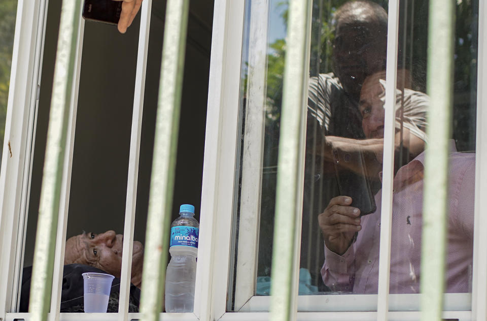 En esta imagen, tomada el 27 de octubre de 2020, el paciente Jose Silva (izquierda) espera a ser evacuado mientras los bomberos sofocan un incendio en el hospital federal Bonsucesso, en Río de Janeiro, Brasil. El fuego comenzó en el sótano de uno de los edificios del hospital y obligó a los equipos de emergencias a evacuar a al menos 200 enfermos, algunos de ellos en sus propias camas. Dos mujeres que estaban graves por COVID-19 murieron durante la evacuación, dijo el hospital. (AP Foto/Silvia Izquierdo)