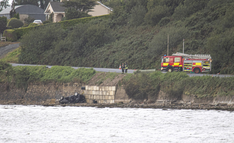 Emergency services attend to the wreckage of the car. (PA Images)