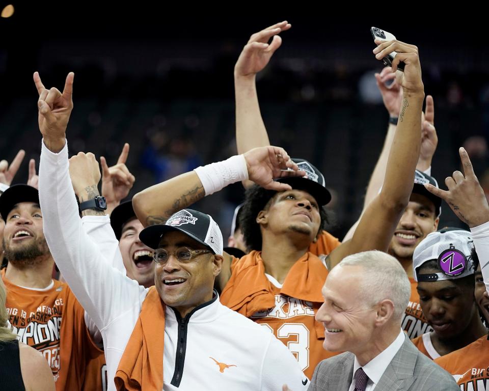 Interim Texas head coach Rodney Terry, front left, celebrates with Big 12 commissioner Brett Yormark, right, after his team won the NCAA college basketball championship game in the Big 12 Conference tournament Saturday, March 11, 2023, in Kansas City, Mo. Texas won 75-56. (AP Photo/Charlie Riedel)