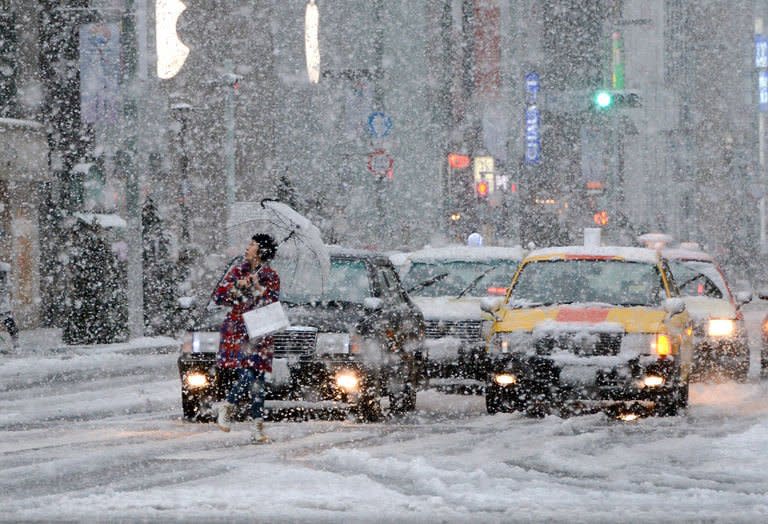 A pedestrian crosses the road in the snow in Tokyo on January 14, 2013. The winter's first snowfall blanketed the Japanese capital and its environs, paralysing traffic and stranding young people taking part in traditional coming-of-age ceremonies