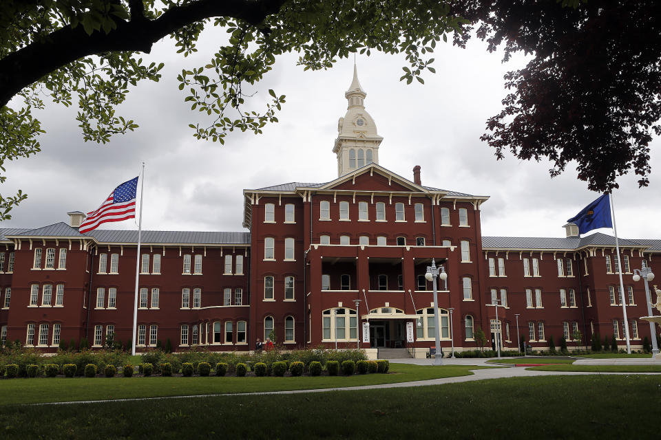 FILE - Flags fly in front of the Oregon State Hospital in Salem, Ore., on May 24, 2013. Oregon State Police say Christopher Pray, newly transferred to Oregon's psychiatric hospital, escaped while fully shackled and drove off in a stolen car. Pray faced charges including attempted murder, robbery, assault and felon in possession of a firearm in Multnomah County Circuit Court, where Portland is located, but was being sent to the Oregon State Hospital in Salem after he was found unfit to proceed with trial, according to court records. (Paul Carter/The Register-Guard via AP, File)