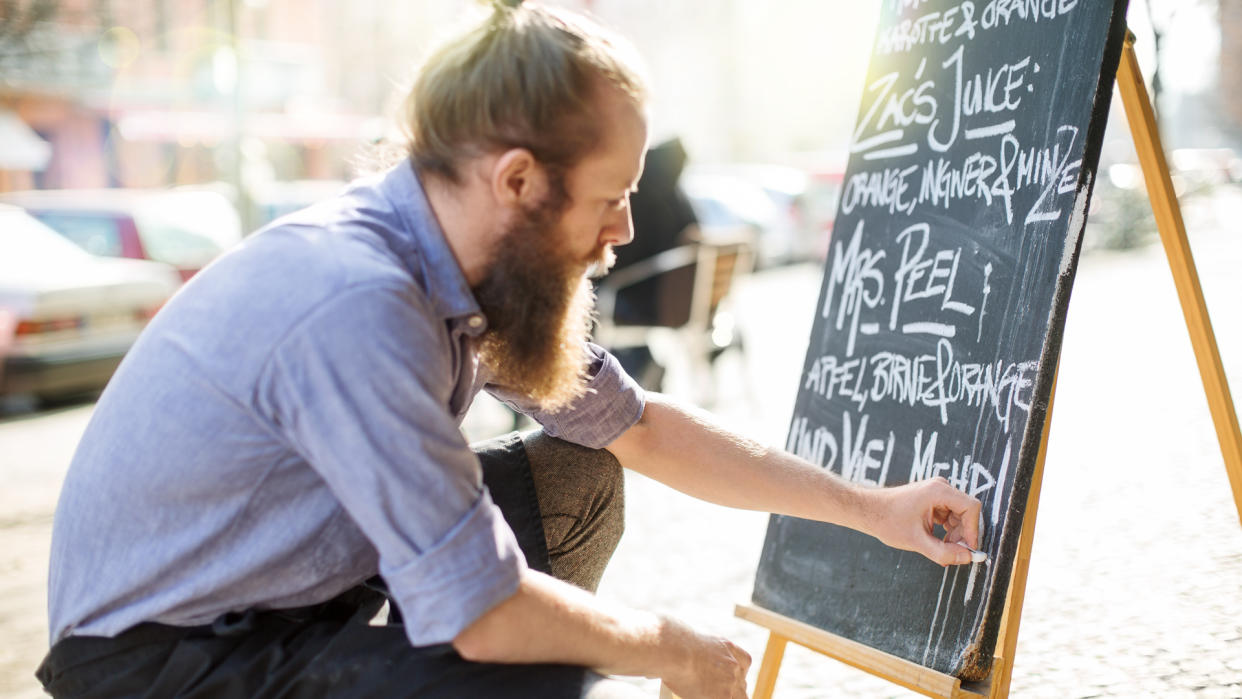 Waiter writing todays special on the board outside the cafe.