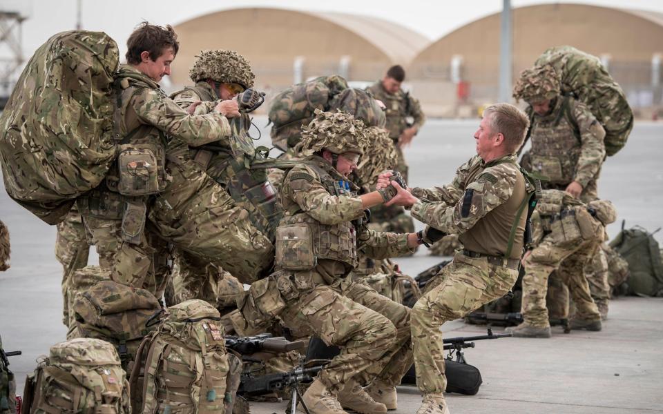 Troops help each other up with heavy Bergen backpacks and weapon systems as some of the last British troops prepare to leave Camp Bastion, as UK and Coalition forces carry out their tactical withdrawal of the the base before handing it over to the Afghan National Army - Ben Birchall /PA