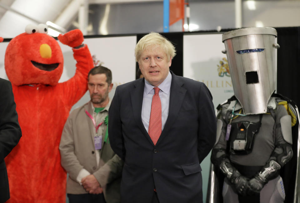 Bobby Smith, a political and fathers' rights activist and founder and leader of the 'Give Me Back Elmo' party, left, and Independent candidate Count Binface stand either side of Britain's Prime Minister and Conservative Party leader Boris Johnson wait for the Uxbridge and South Ruislip constituency count declaration at Brunel University in Uxbridge, London, Friday, Dec. 13, 2019. (AP Photo/Kirsty Wigglesworth)