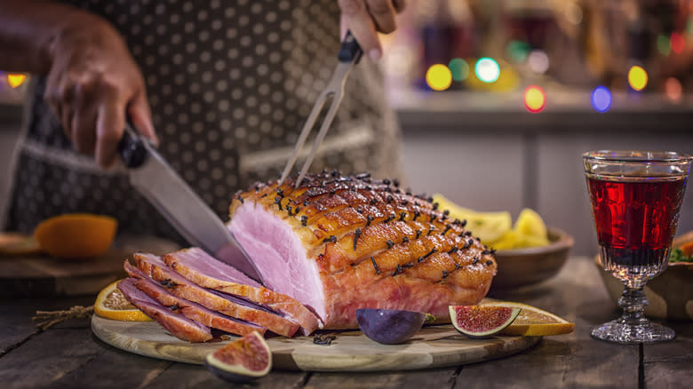 Person cutting oven-baked ham