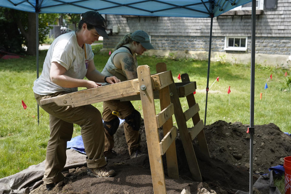 University of Massachusetts Boston research scientist Christa Beranek, of Arlington, Mass., left, and UMass graduate student Emily Willis, of Boston, right, sift soil through screens while searching for artifacts at an excavation site, Wednesday, June 9, 2021, on Cole's Hill, in Plymouth, Mass. The archaeologists are part of a team excavating the grassy hilltop that overlooks iconic Plymouth Rock one last time before a historical park is built on the site. (AP Photo/Steven Senne)