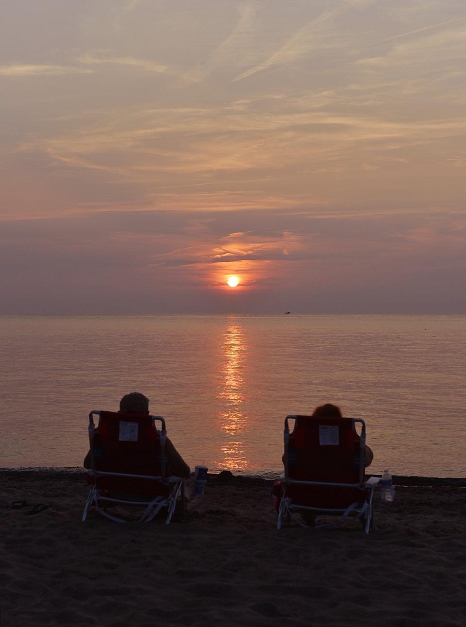 A couple watches the sun set on Lake Erie on July 20, 2014, near the Presque Isle Lighthouse at Presque Isle State Park.