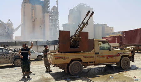 Members of forces loyal to Libya's eastern government stand near to the Libyan cement factory after the army took control of the factory following clashes with the Shura Council of Libyan Revolutionaries, an alliance of former anti-Gaddafi rebels who have joined forces with Islamist group Ansar al-Sharia, in Benghazi, Libya April 18, 2016. REUTERS/Stringer