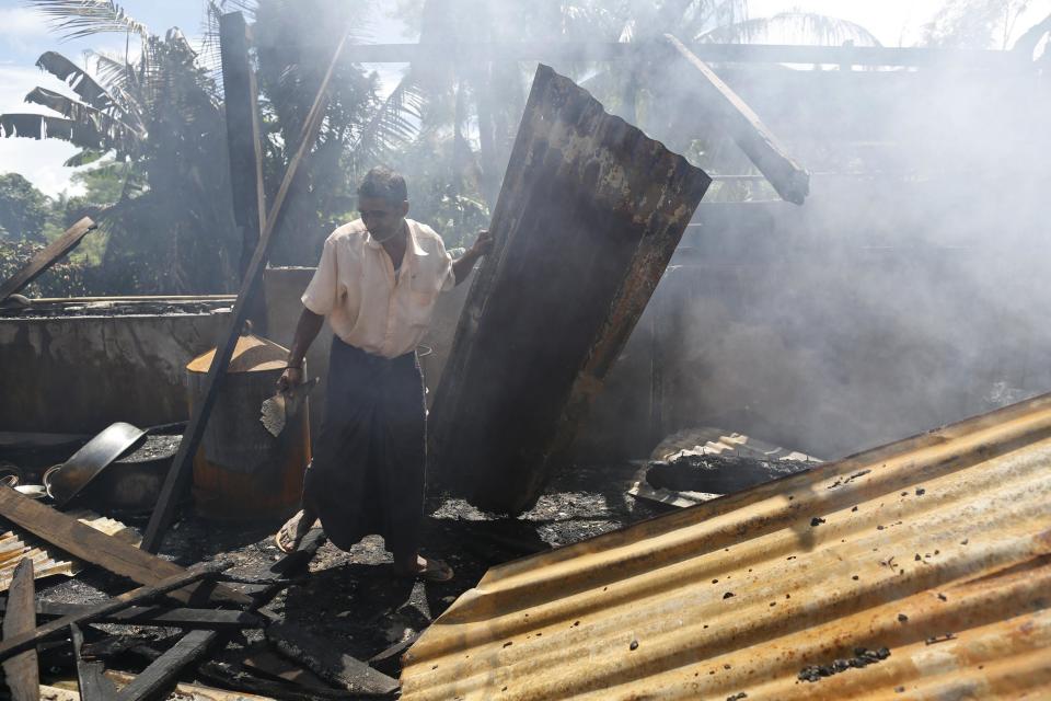 A man clears debris from the mosque that was burnt down in recent violence at Thapyuchai village