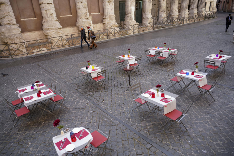 People walk past the empty tables of a caffe', in Rome's central Piazza di Pietra, Wednesday, Nov. 25, 2020. (AP Photo/Andrew Medichini)