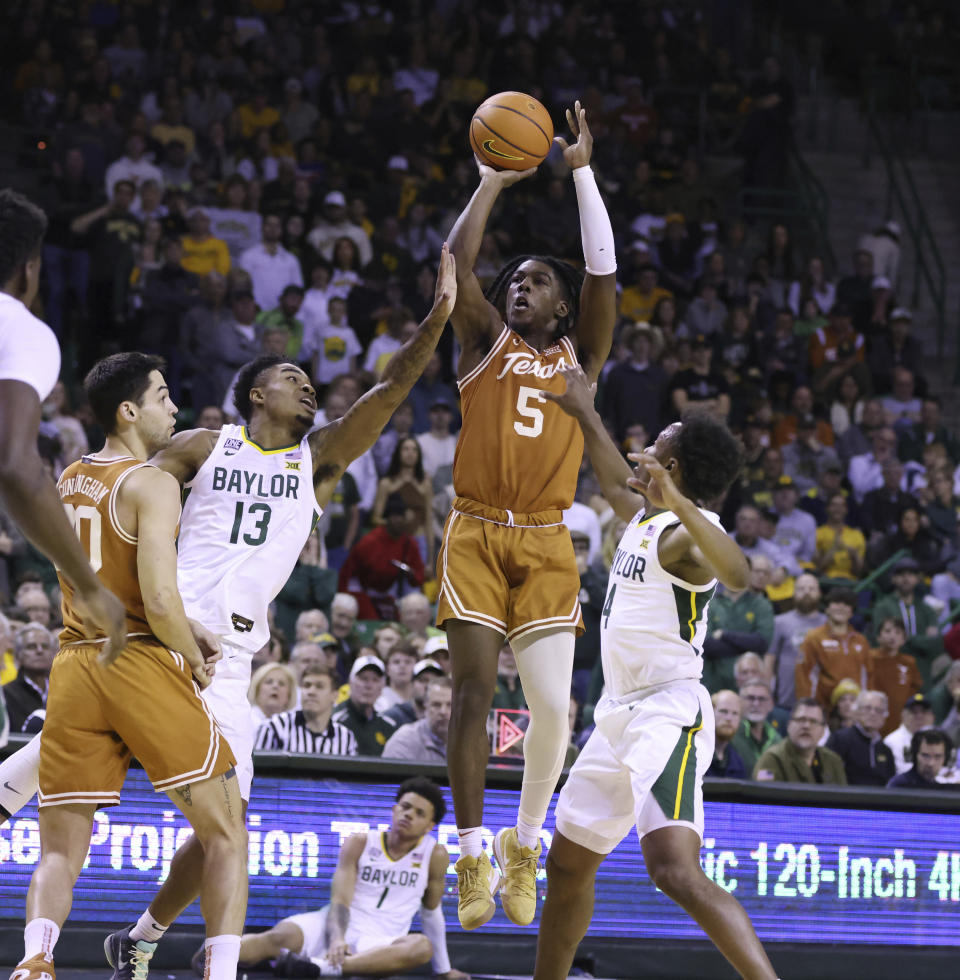 Texas guard Marcus Carr (5) shoots between Baylor guard Langston Love (13) and guard LJ Cryer (4) in the first half of an NCAA college basketball game, Saturday, Feb. 25, 2023, in Waco, Texas. (Rod Aydelotte/Waco Tribune-Herald via AP)