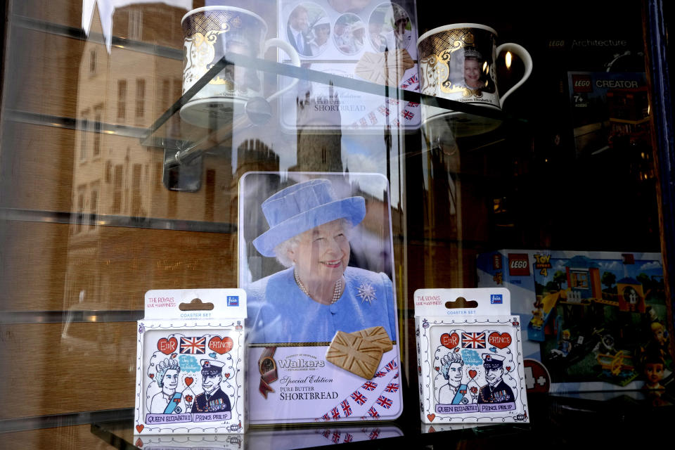 Windsor Castle is reflected in the window of a shop selling Royal souvenirs outside the Castle, in Windsor, England, Friday, Oct. 22, 2021. Britain's Queen Elizabeth II spent a night in a hospital for checks this week after canceling an official trip to Northern Ireland on medical advice, Buckingham Palace said Thursday. The palace said the 95-year-old British monarch went to the private King Edward VII's Hospital in London on Wednesday for "preliminary investigations." It said she returned to her Windsor Castle home at lunchtime on Thursday, "and remains in good spirits."(AP Photo/Kirsty Wigglesworth)