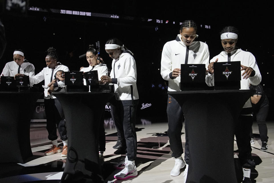 Las Vegas Aces react as they open boxes with their 2023 championship rings before a WNBA basketball game Tuesday, May 14, 2024, in Las Vegas. (AP Photo/John Locher)