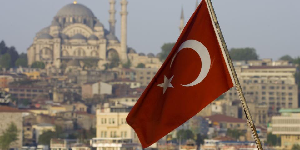 Turkish flag on back of boat on the Bosphorus and Mosque on hillside in Istanbul, Turkey.