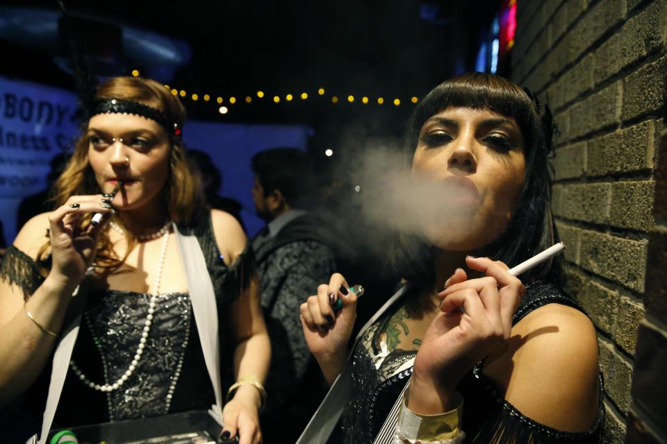 FILE - In this Dec. 31, 2013 file photo, partygoers smoke marijuana during a Prohibition-era themed New Year's Eve invite-only party celebrating the start of retail pot sales, at a bar in Denver. Colorado is on the brink of becoming the first state with licensed pot clubs. Denver officials are working on regulations to open a one-year pilot of bring-your-own marijuana clubs. (AP Photo/Brennan Linsley, file)